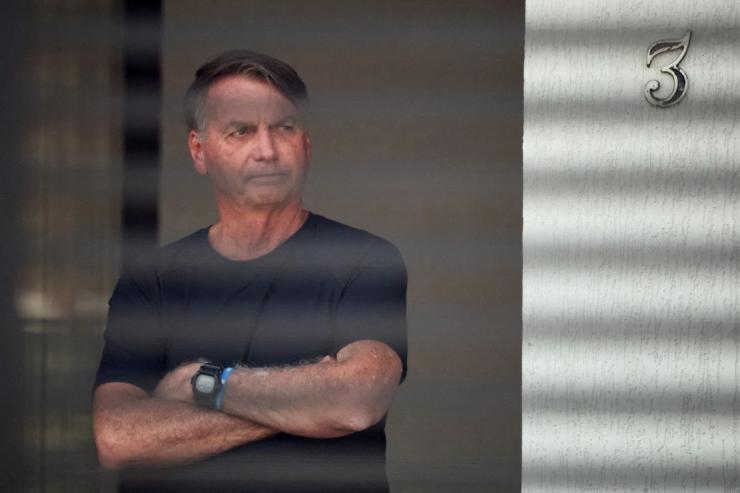 Brazil’s former President Jair Bolsonaro stands at his home while under house arrest.