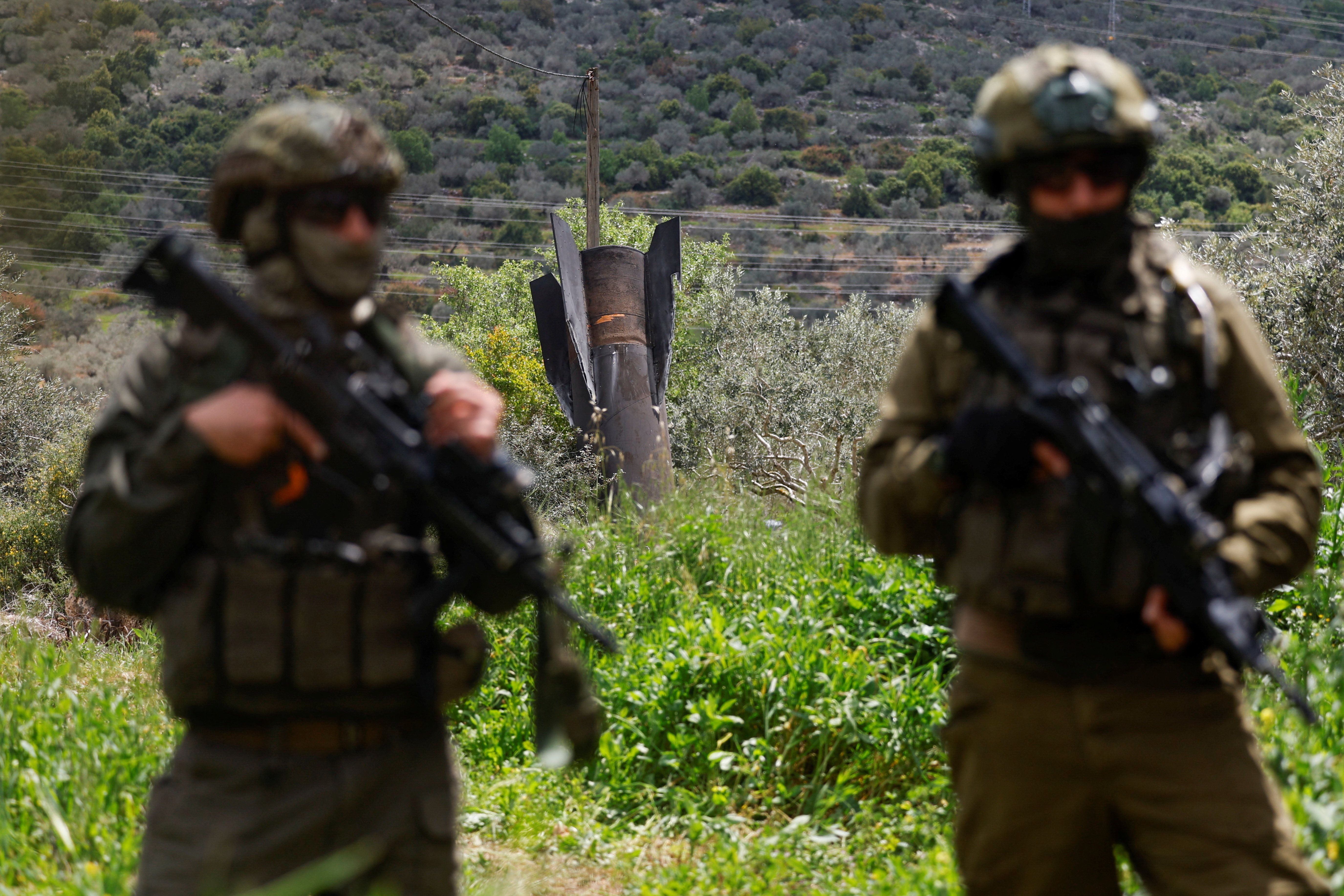 Israeli soldiers stand guard near remnants of a missile stuck in the ground found in Kifl Haris village, near Nablus in the Israeli-occupied West Bank