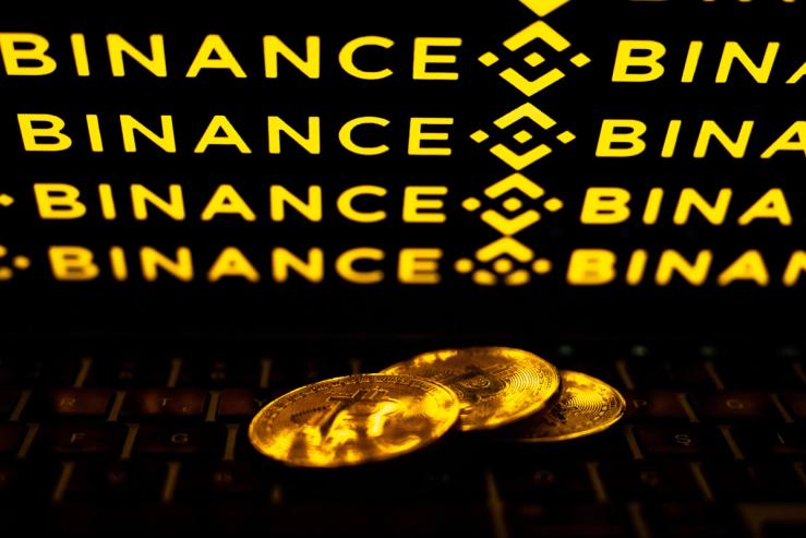 In this photo illustration Bitcoin cryptocurrency coins are seen in front of a screen displaying ‘Binance’ logo.