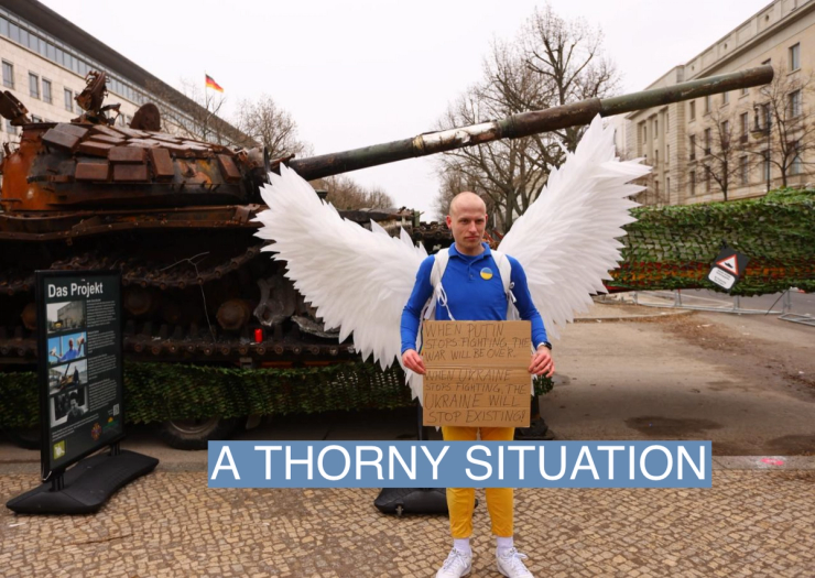 A protester next to remains of a destroyed Russian T-72 tank in Berlin on Feb. 24, 2023