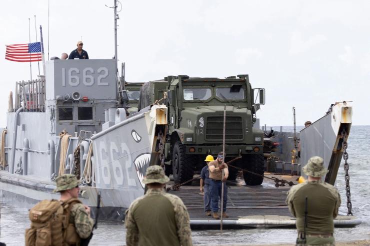 A U.S. Navy sailor uses a measuring stick to check water depth as the landing craft utility (LCU-1662) rests on the shore during training exercises in Arroyo