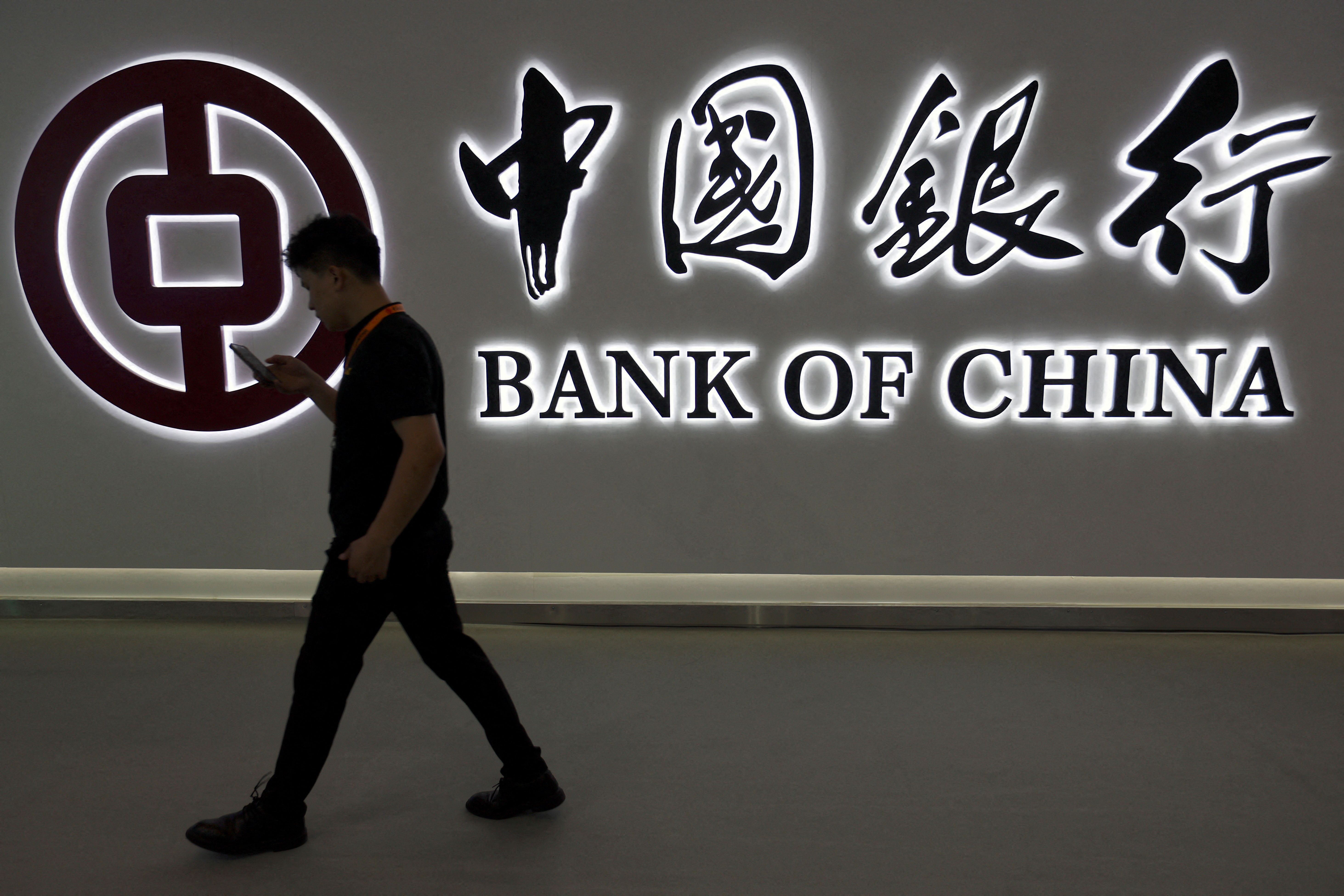 A man walks past the Bank of China logo.
