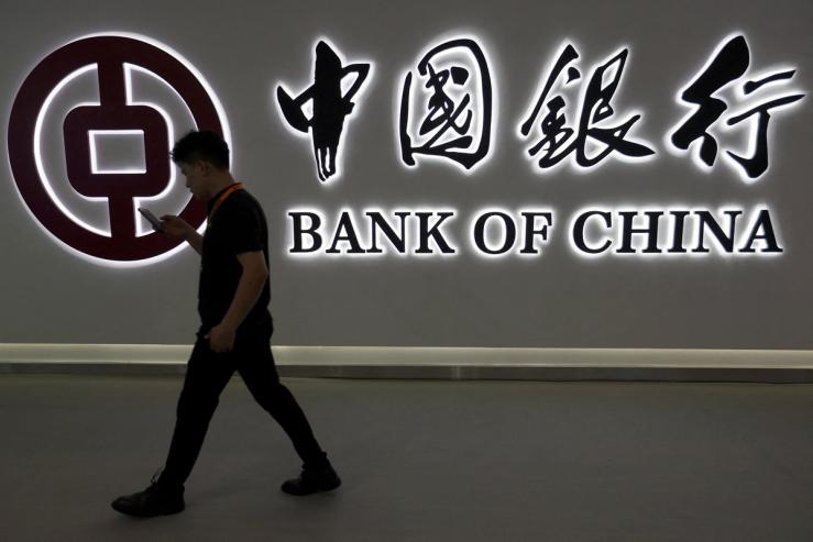 A man walks past the Bank of China logo.