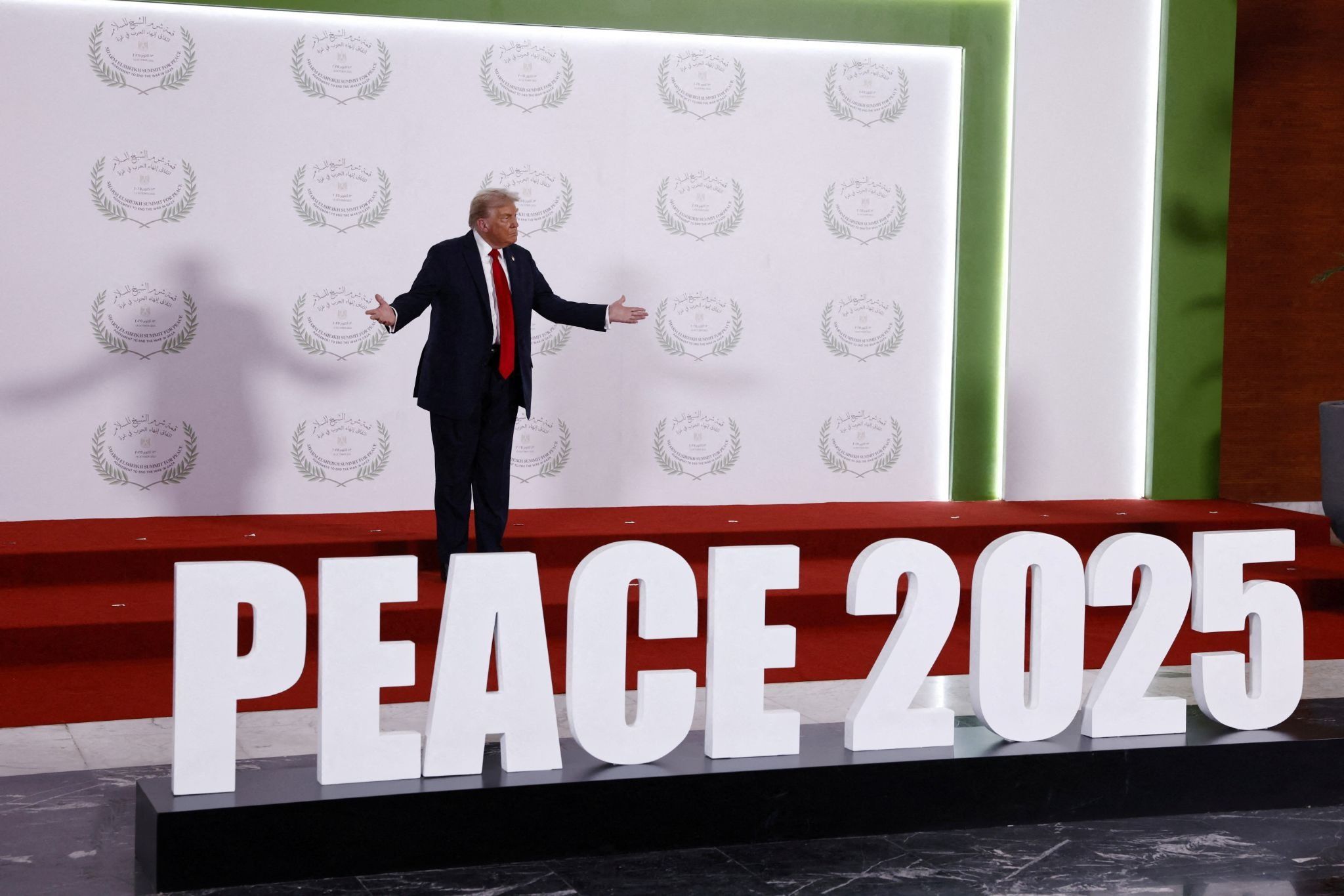 US President Donald Trump waits to greet world leaders in Egypt in front of a ‘Peace 2025’ sign.