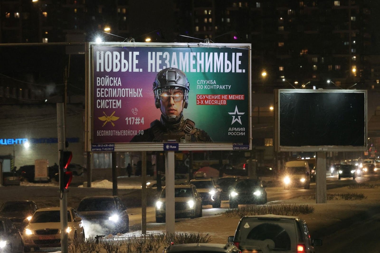Cars drive past a board promoting military contract service in the Russian army in St Petersburg