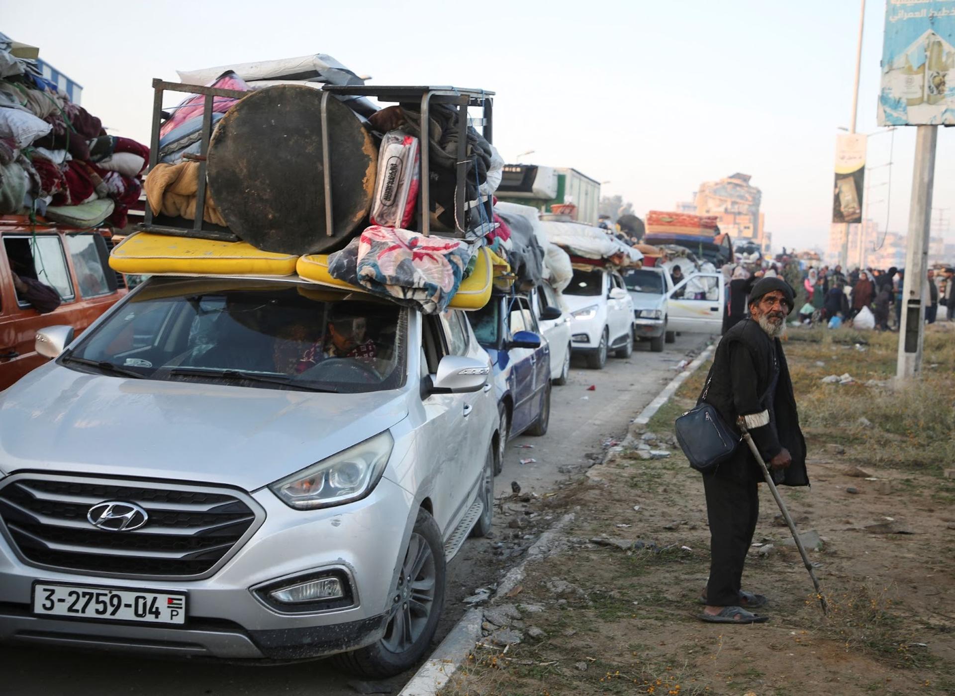 An elderly man stands beside a line of cars in Gaza.