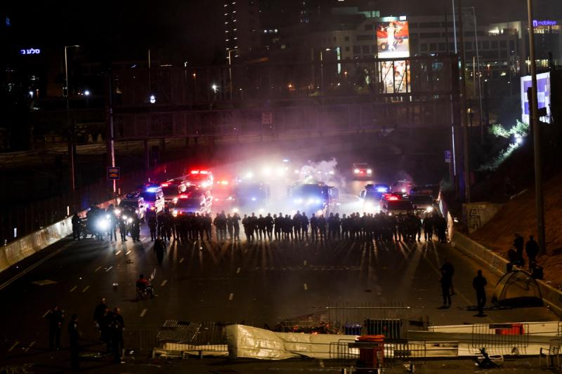 Members of security forces stand guard as people attend a demonstration after Israeli Prime Minister Benjamin Netanyahu dismissed the defense minister and his nationalist coalition government presses on with its judicial overhaul, in Tel Aviv, Israel, March 27, 2023. REUTERS/Nir Elias