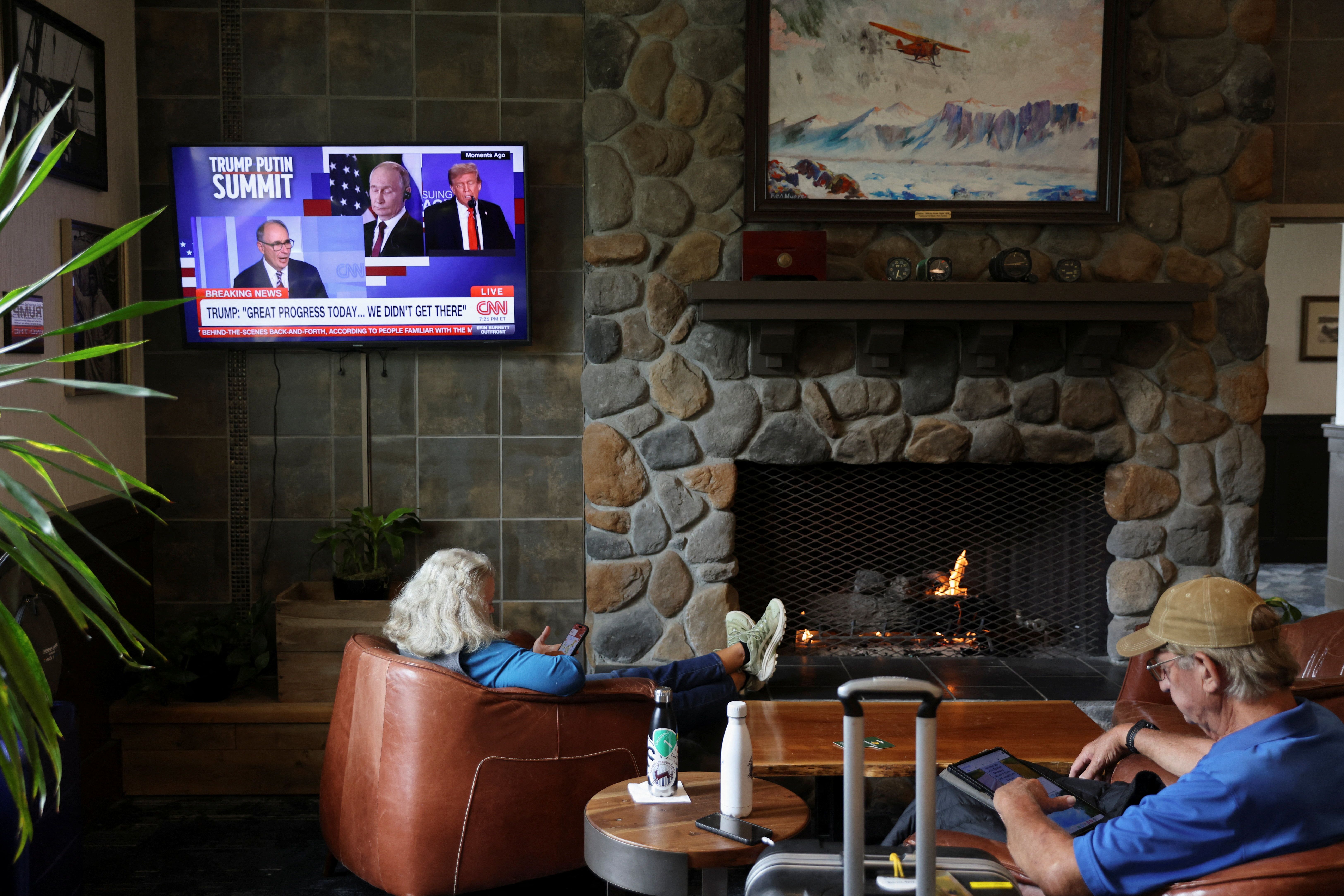 People sit next to a TV showing a CNN broadcast