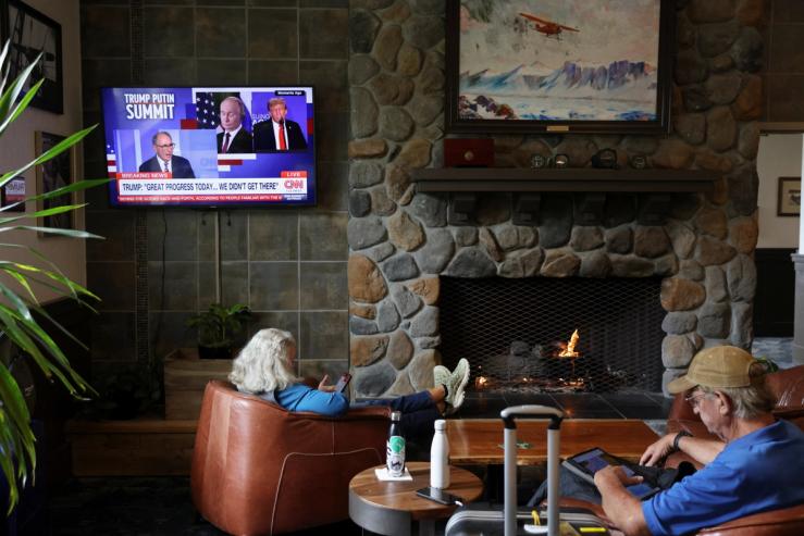 People sit next to a TV showing a CNN broadcast