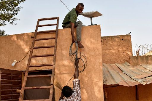 A technician mounts a Starlink satellite dish in Niger.
