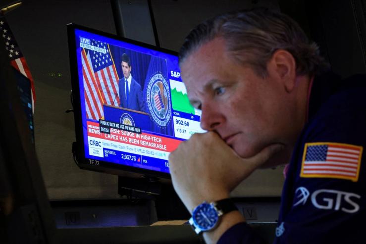 Traders look on as Warsh gives a speech.