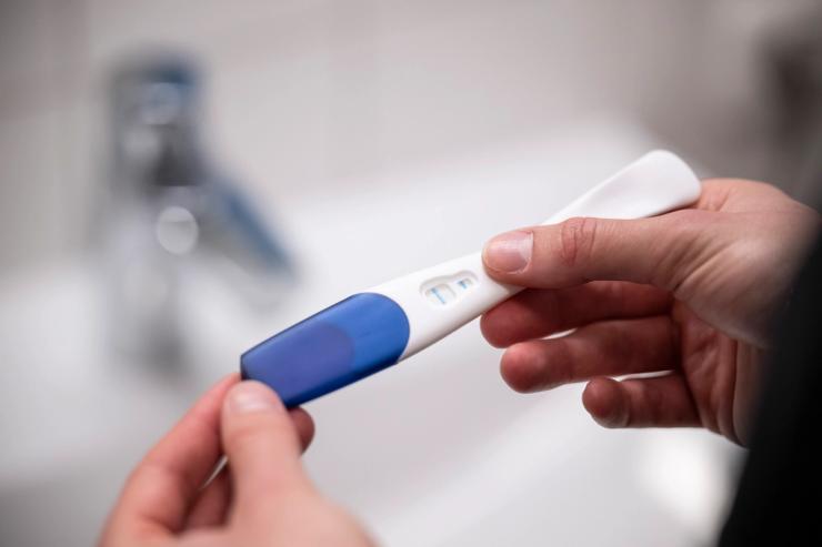 A woman holds a pregnancy test.
