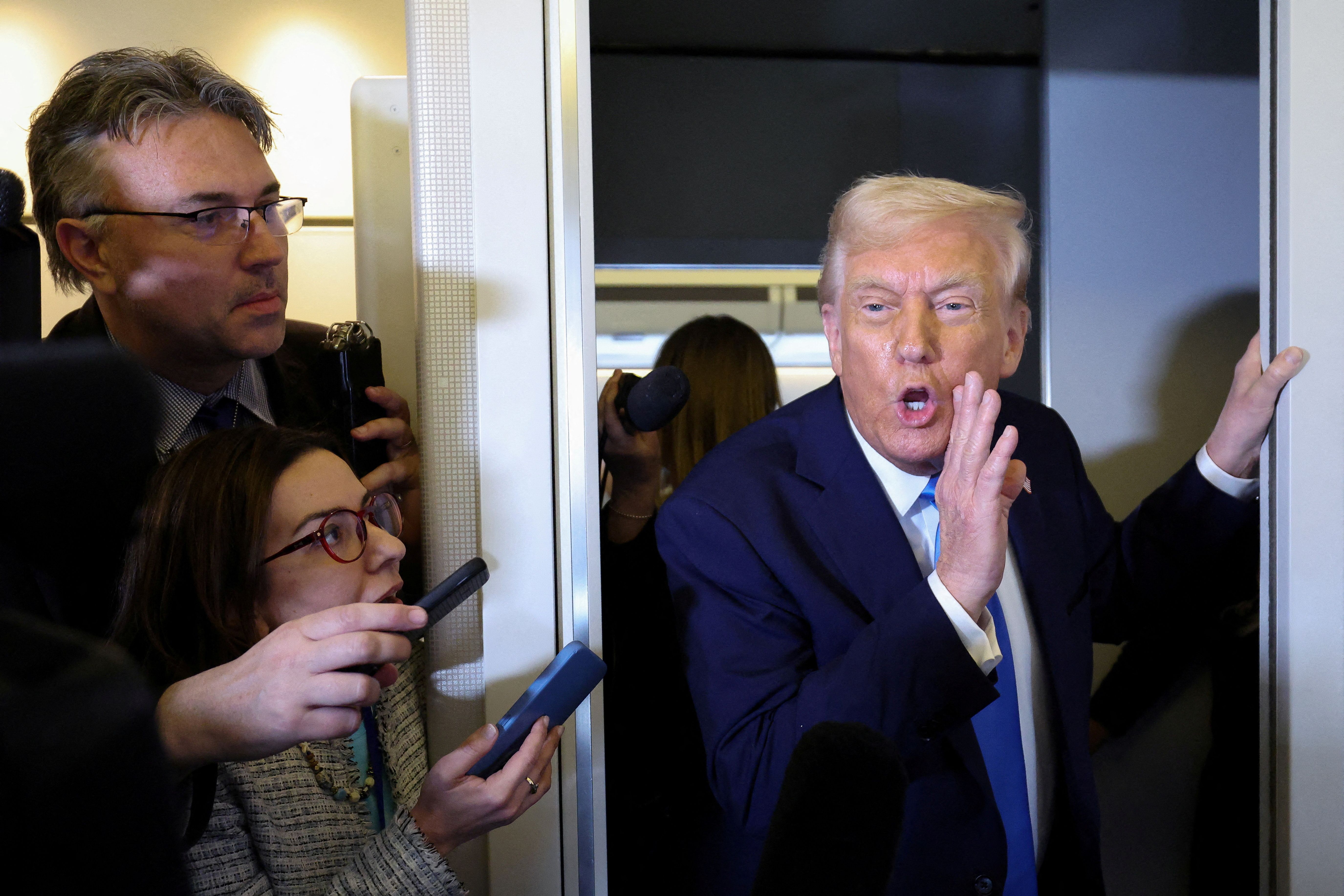 US President Donald Trump speaks to members of the media aboard Air Force One before landing in West Palm Beach.