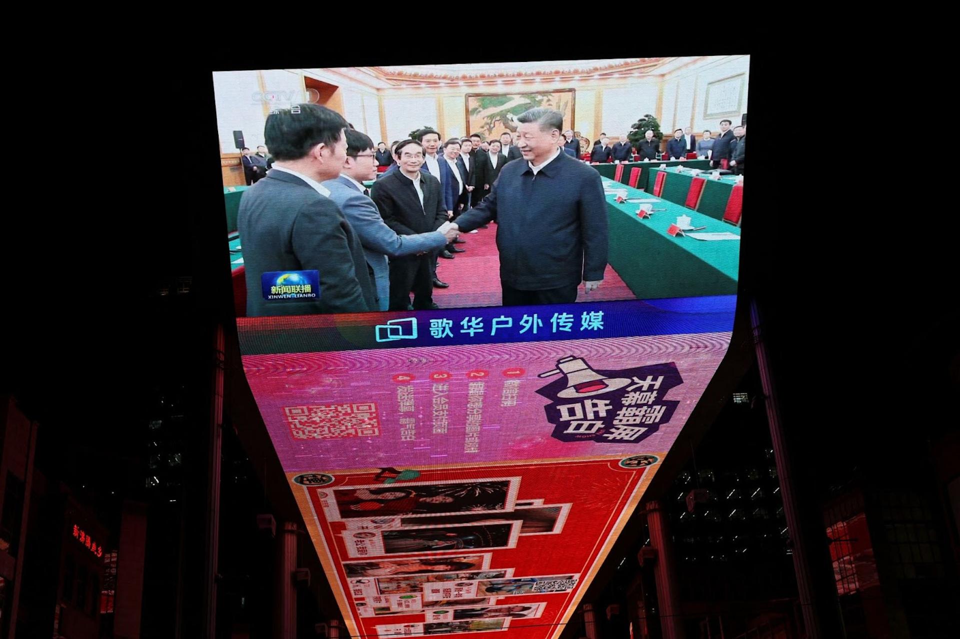 A digital display showing China’s President Xi Jinping meeting with business leaders.