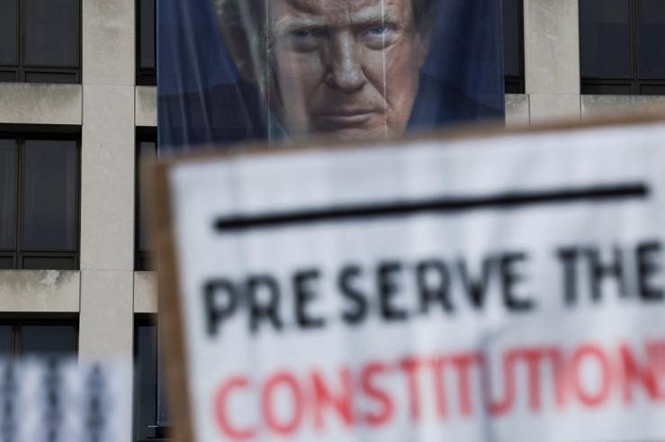 Protesters in front of a banner depicting Donald Trump