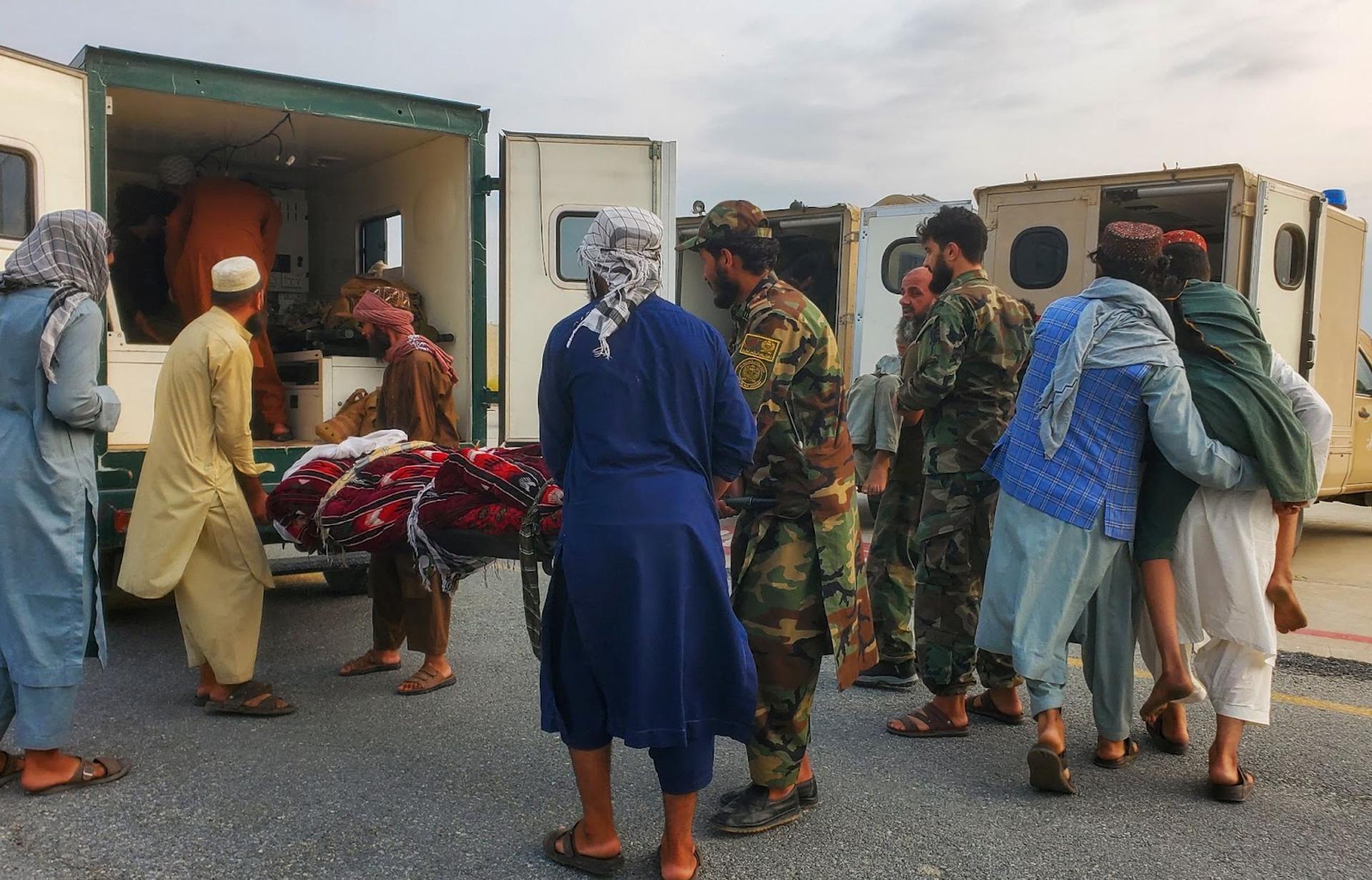 Taliban soldiers and civilians carry earthquake victims to an ambulance at an airport in Jalalabad. 