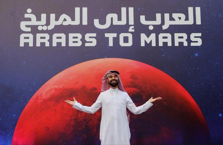 Man posing in front of a sign that says Arabs to Mars during an event to mark Hope Probe entering the Red Planet’s orbit.