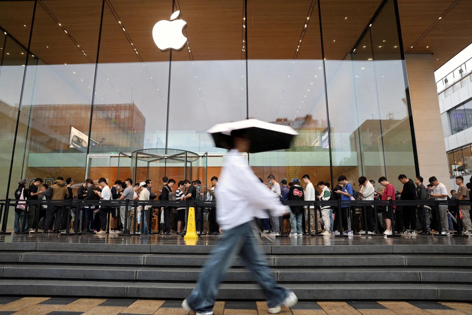 People line up outside an Apple store on a rainy day in Beijing, China.