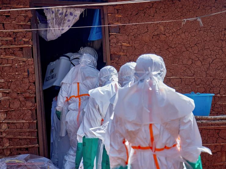 Red Cross workers wearing personal protective equipment (PPE) disinfect the house of many who died of Ebola.