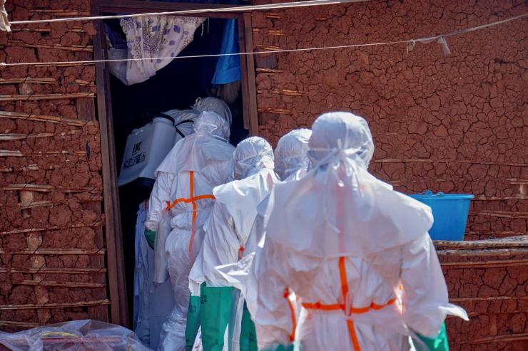 Red Cross workers wearing personal protective equipment (PPE) disinfect the house of many who died of Ebola.