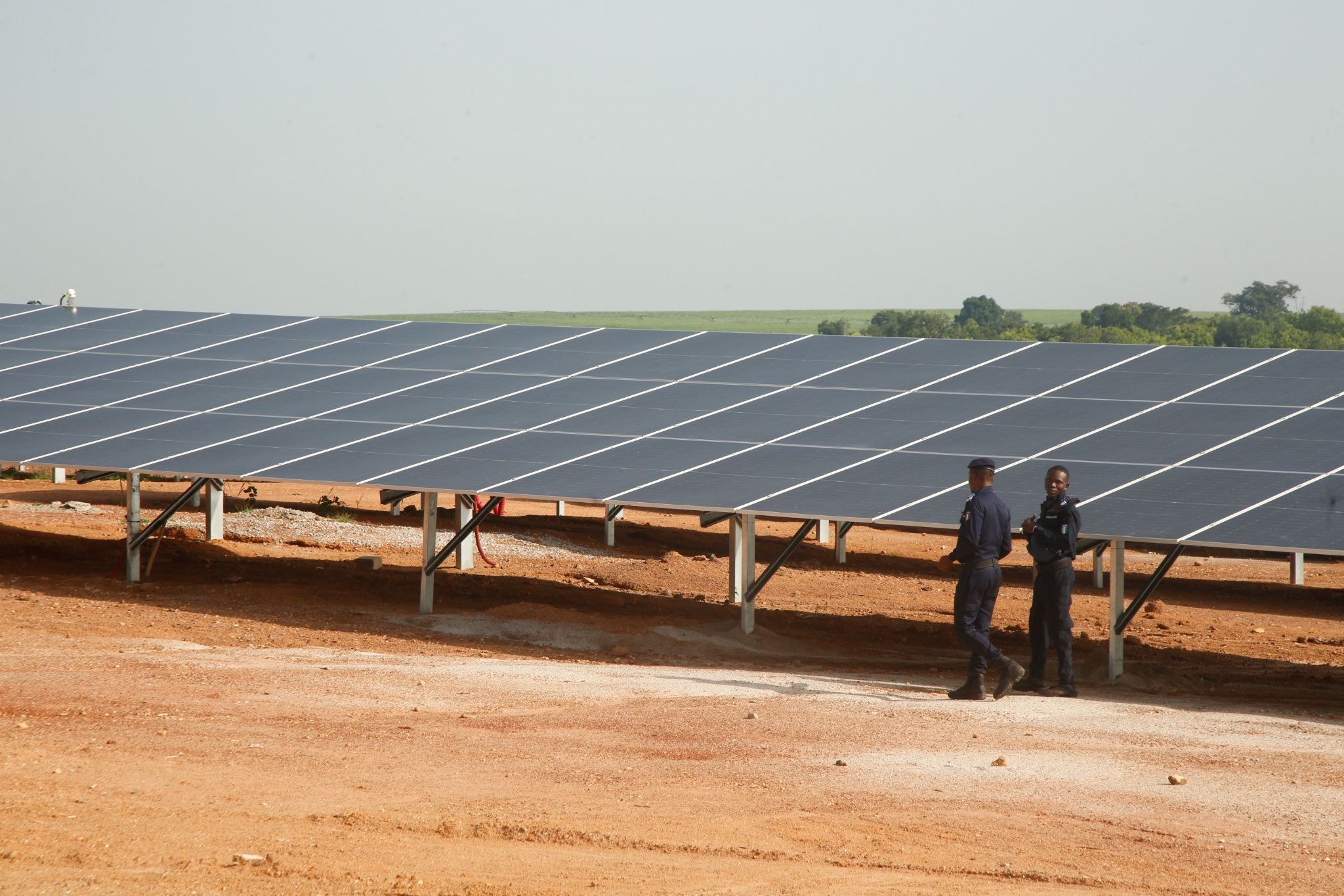 Security forces members walk past solar panels at the Ferke Solar photovoltaic power plant, developed by PFO Energies, a subsidiary of PFO Africa Group, during its inauguration ceremony in Ferkessedougou, northern Ivory Coast, July 3, 2026. 