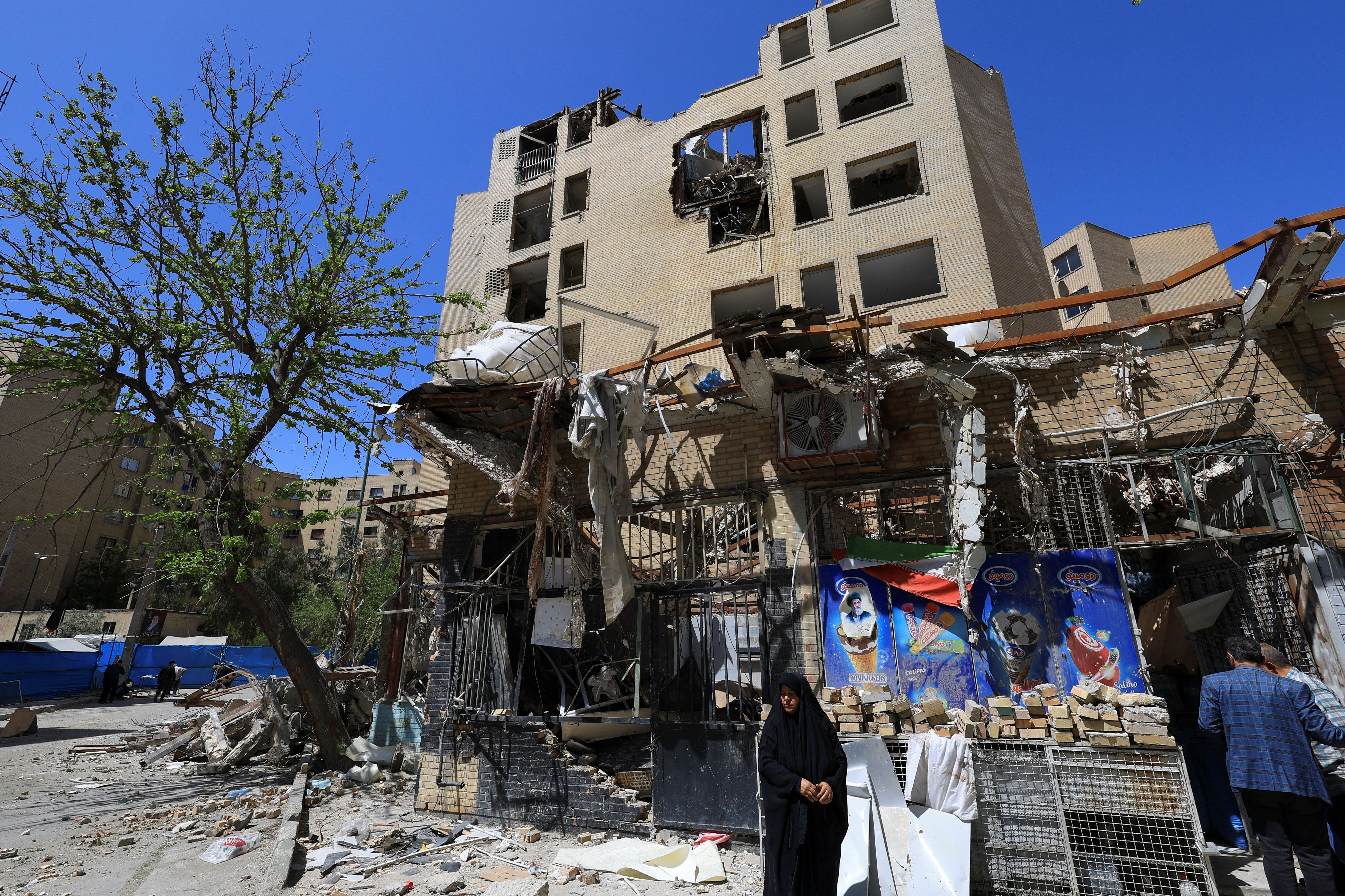 A woman stands next to debris lying in front of a residential building damaged by a strike on March 4, in Tehran.