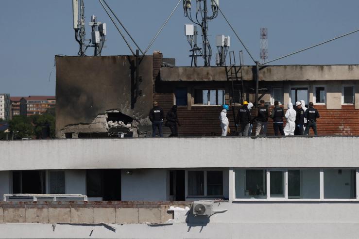 Romanian law enforcement officers work at the site of an explosion in a residential block of flats.