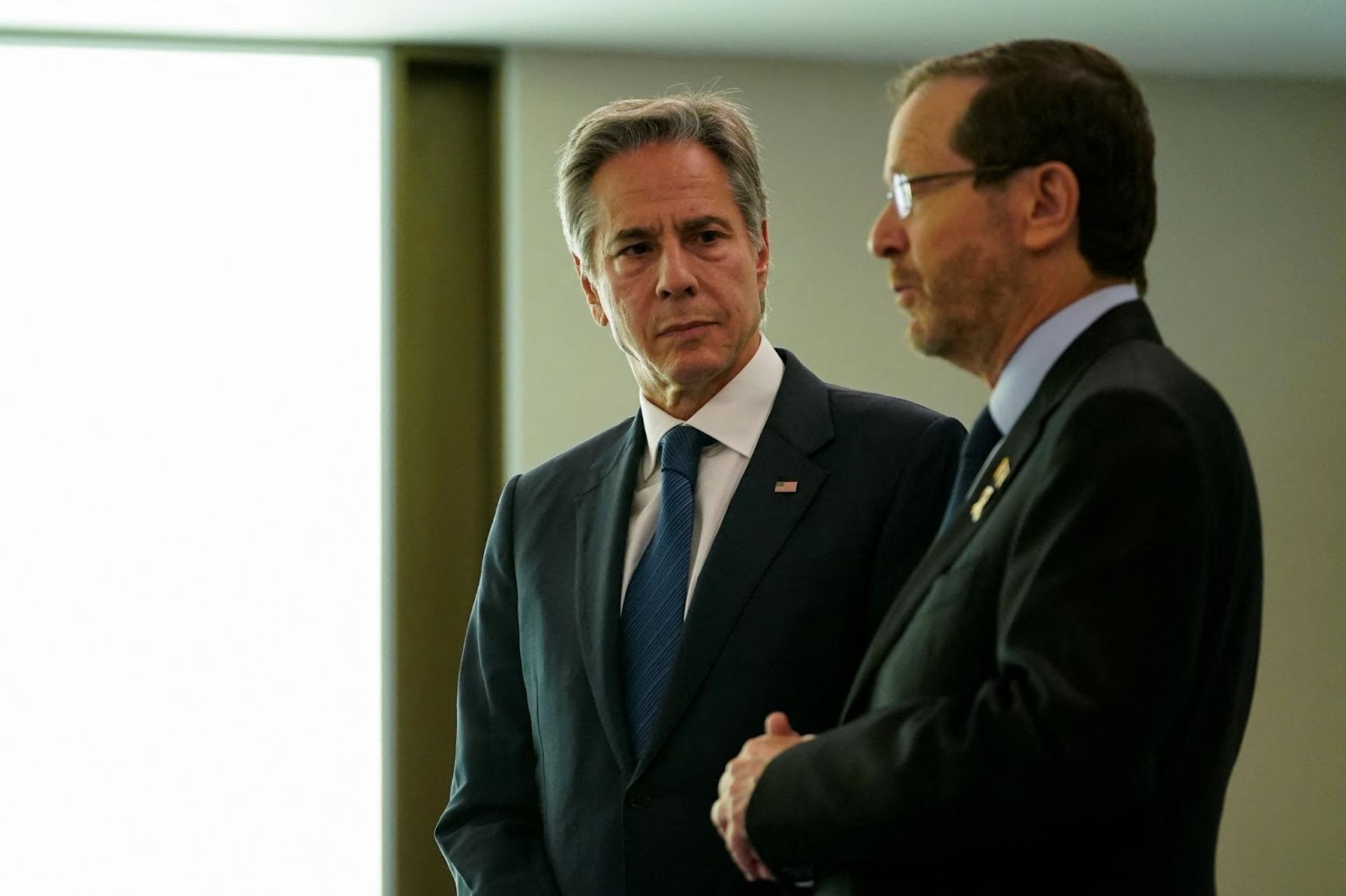 Antony Blinken, wearing a dark suit and tie, stands next to Israeli President Isaac Herzog at a press conference in Tel Aviv 