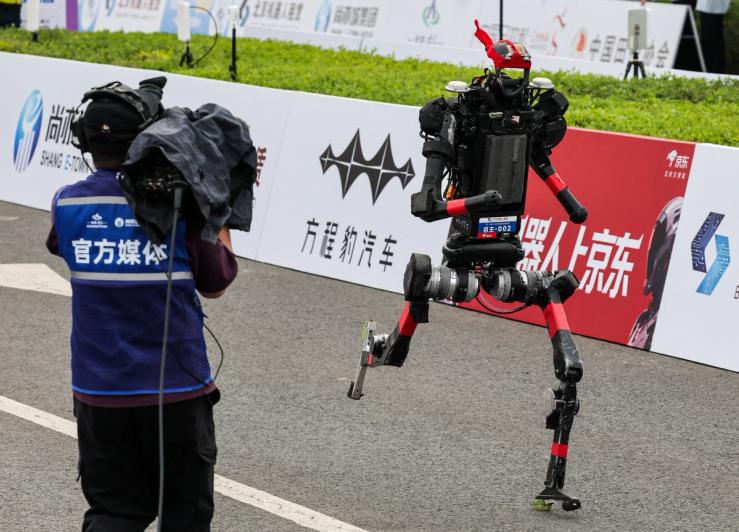 A cameraman films as a Unitree H1 humanoid robot runs