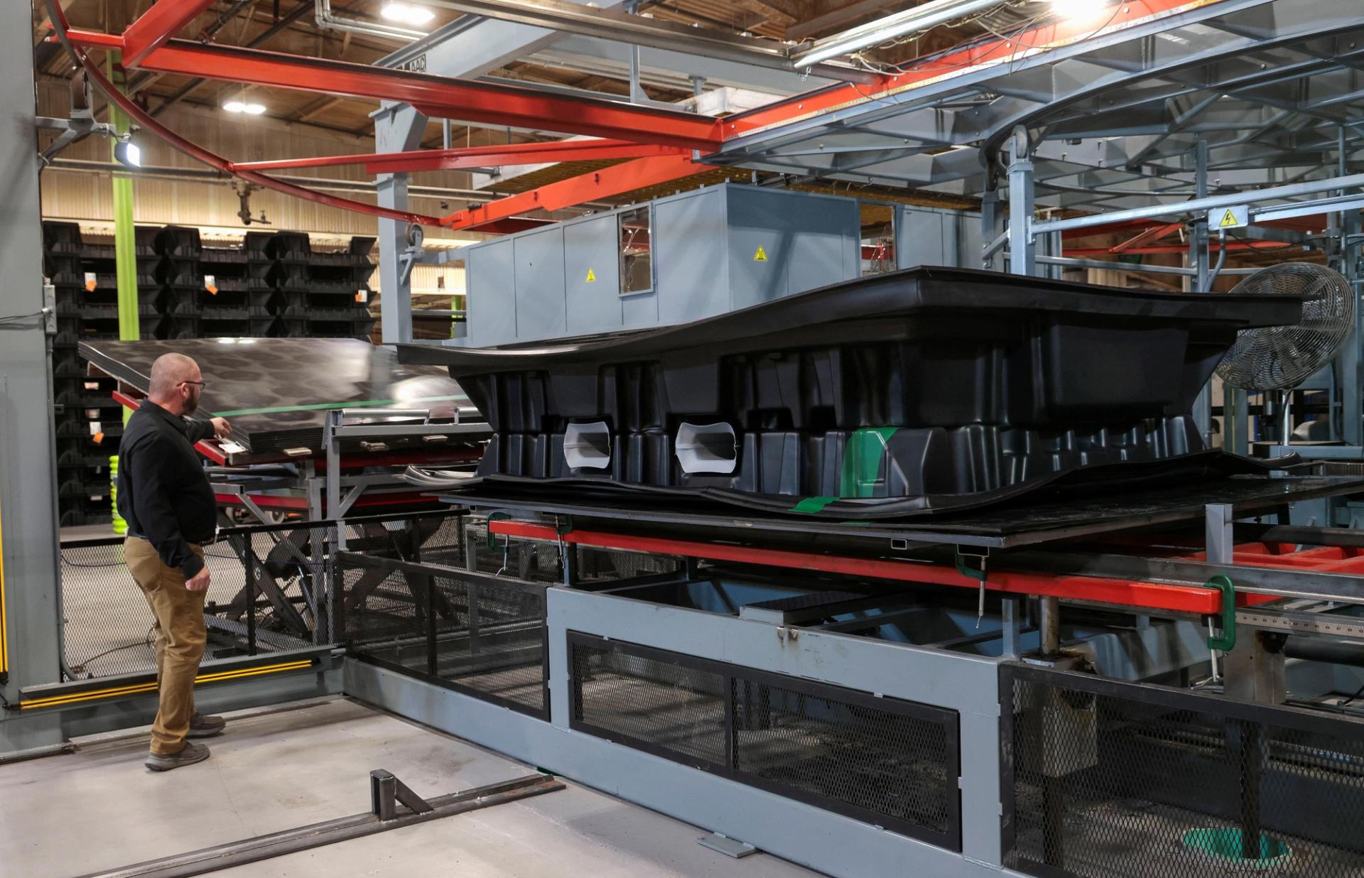 A worker at plastic manufacturing Vantage Plastics shows the thermoforming machine used to manufacture pallets for EV batteries. 