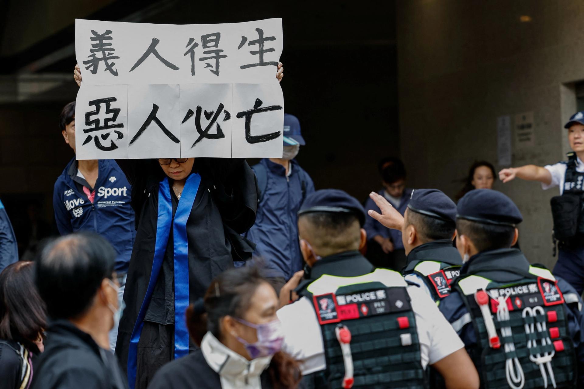 Elsa, the foster mother of one of the defendants, social worker Hendrick Lui, holds a banner reading “The righteous shall live; the wicked shall perish” outside the West Kowloon Magistrates’ Courts building