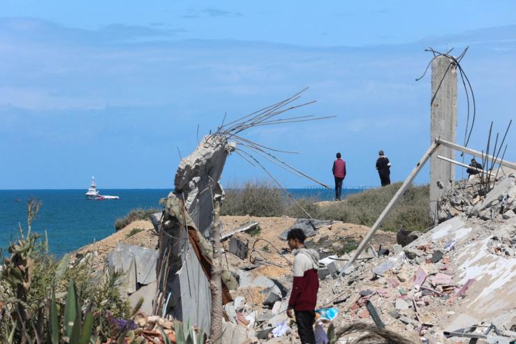 People watch as ship carrying aid sails off the shore of Gaza, amid the ongoing conflict between Israel and the Palestinian Islamist group Hamas, as seen from central Gaza Strip, March 15, 2024. REUTERS/Ahmed Zakot TPX IMAGES OF THE DAY