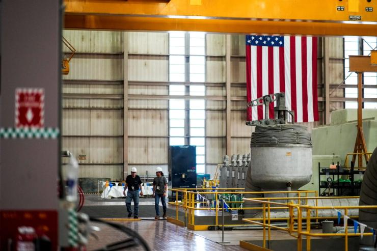 Constellation Energy workers walk near a generator in the turbine hall at the former Three Mile Island Nuclear power plant.