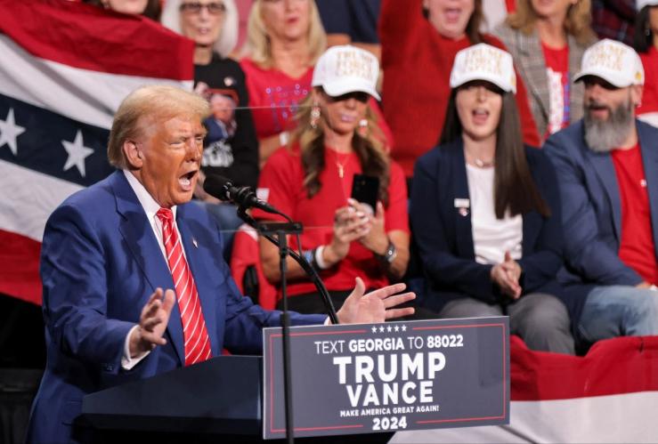 Donald Trump, wearing a blue suit and red tie, speaks during a campaign event in Atlanta, Georgia