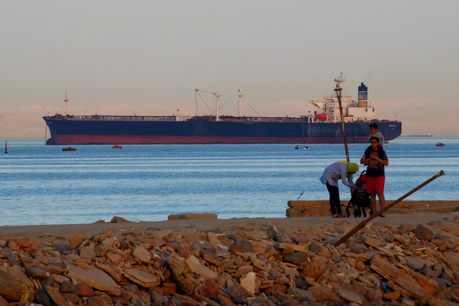 FILE PHOTO: People walk on the beach as a container ship crosses the Gulf of Suez towards the Red Sea before entering the Suez Canal, in El Ain El Sokhna in Suez, east of Cairo, Egypt April 24, 2017. REUTERS/Amr Abdallah Dalsh/File Photo