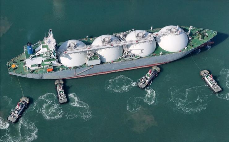 A drone view shows tugboats assisting a liquified natural gas (LNG) tanker to dock at a port in Yantai, Shandong province.