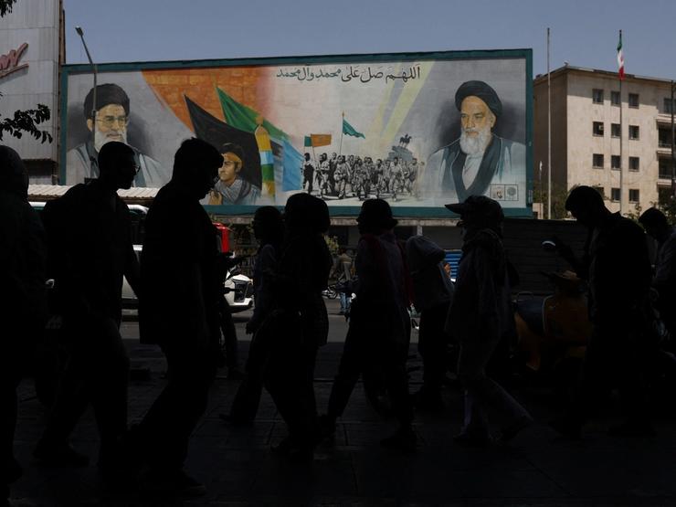 People walk past a mural depicting the late leader of the Islamic Revolution, Ayatollah Ruhollah Khomeini, and Iran’s late Supreme Leader Ayatollah Ali Khamenei, on a street in Tehran.