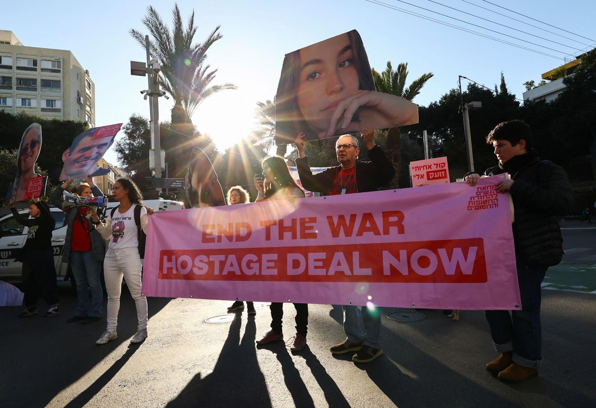 Demonstrators hold a poster and cutouts of images of hostages during a protest near the Likud party headquarters in Tel Aviv.