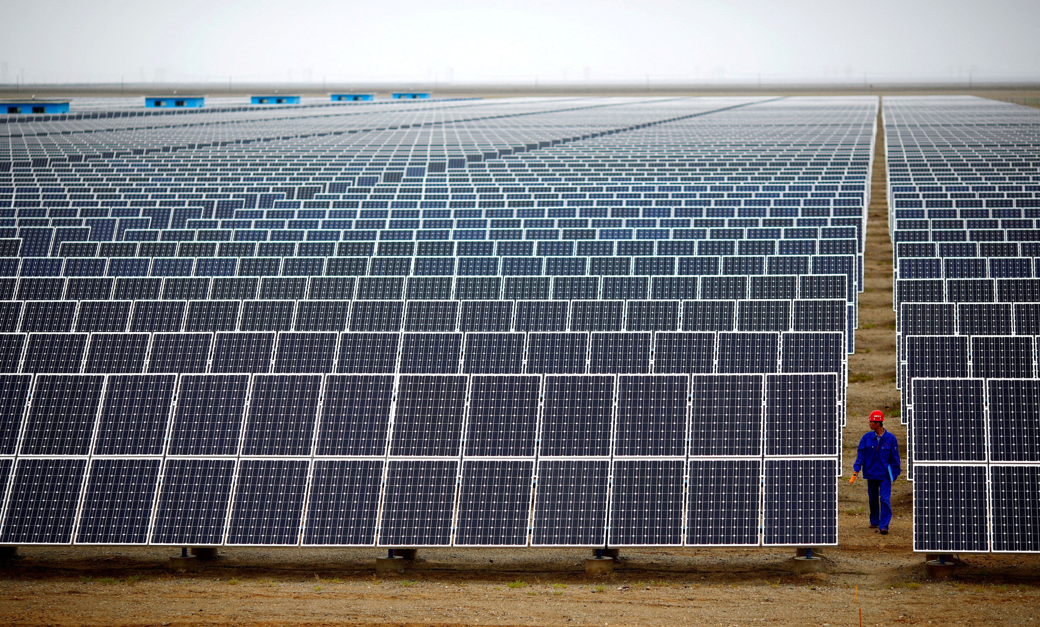 A worker inspects solar panels at a solar farm in the Gansu Province, China. 