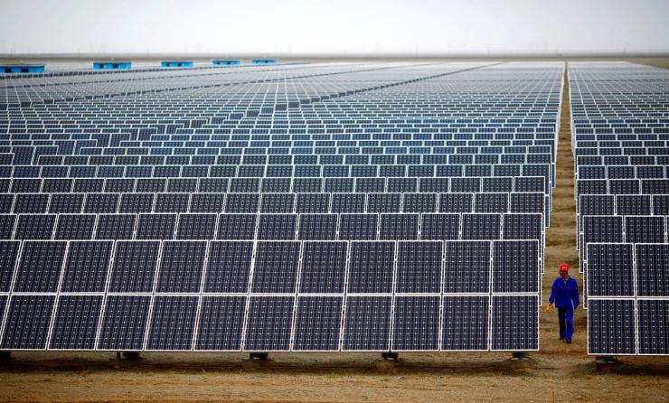 A worker inspects solar panels at a solar farm in Dunhuang, China.