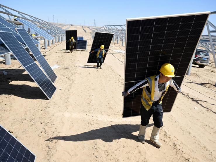 Workers carry solar panels in China.