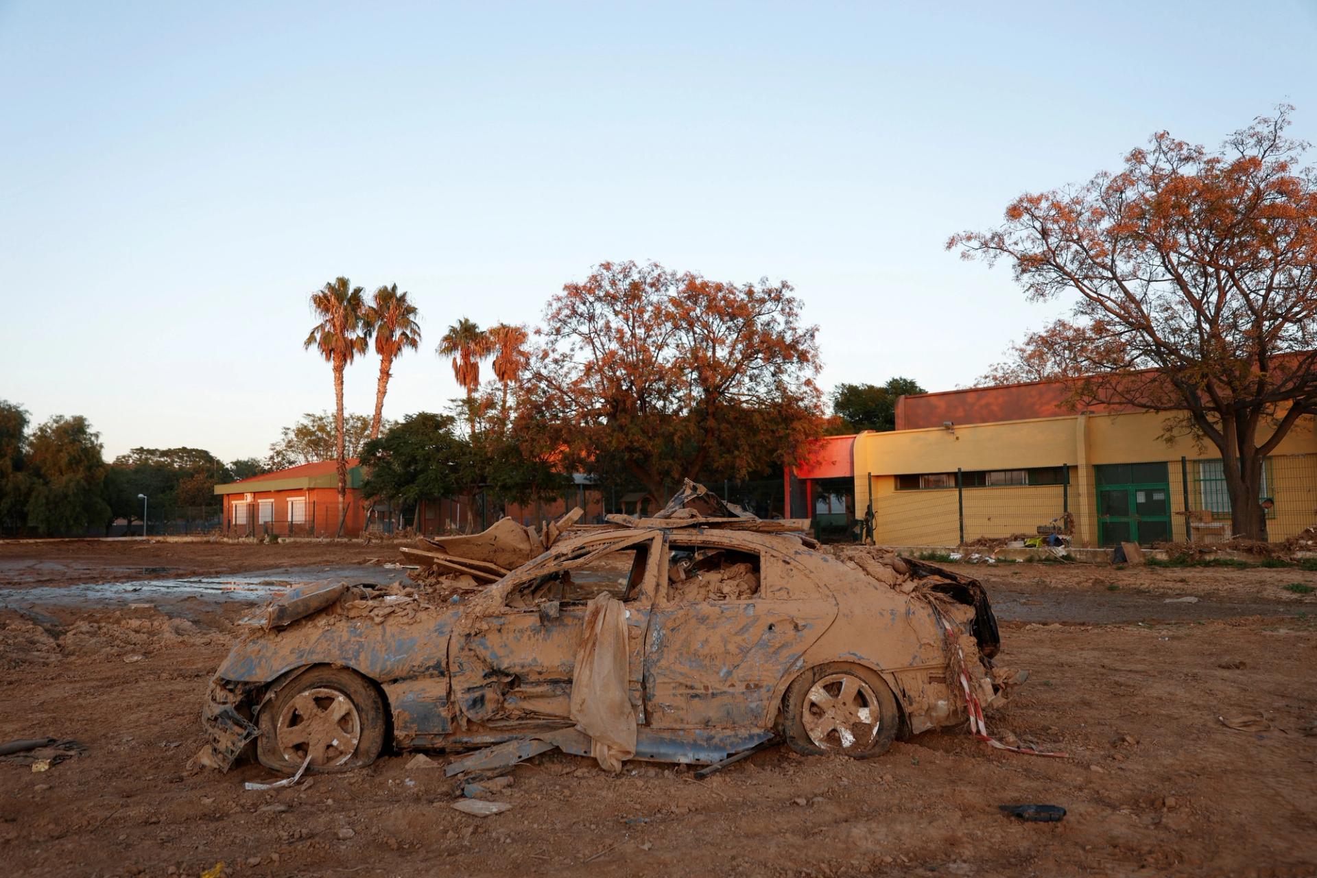 Nearly a month after severe flooding, a damaged car lies in front of a high school in Paiporta, Valencia, Spain.