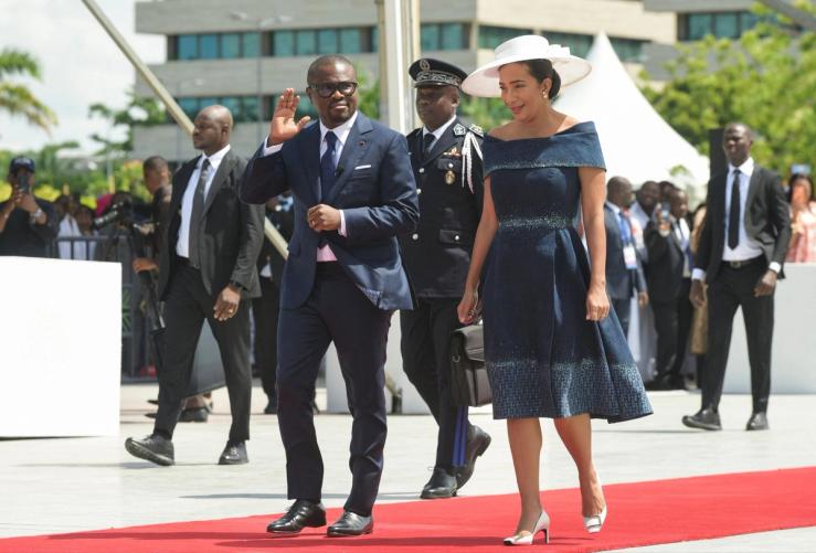 Benin’s President Romuald Wadagni waves as he walks next to his wife Nathalie Villette-Wadagni.