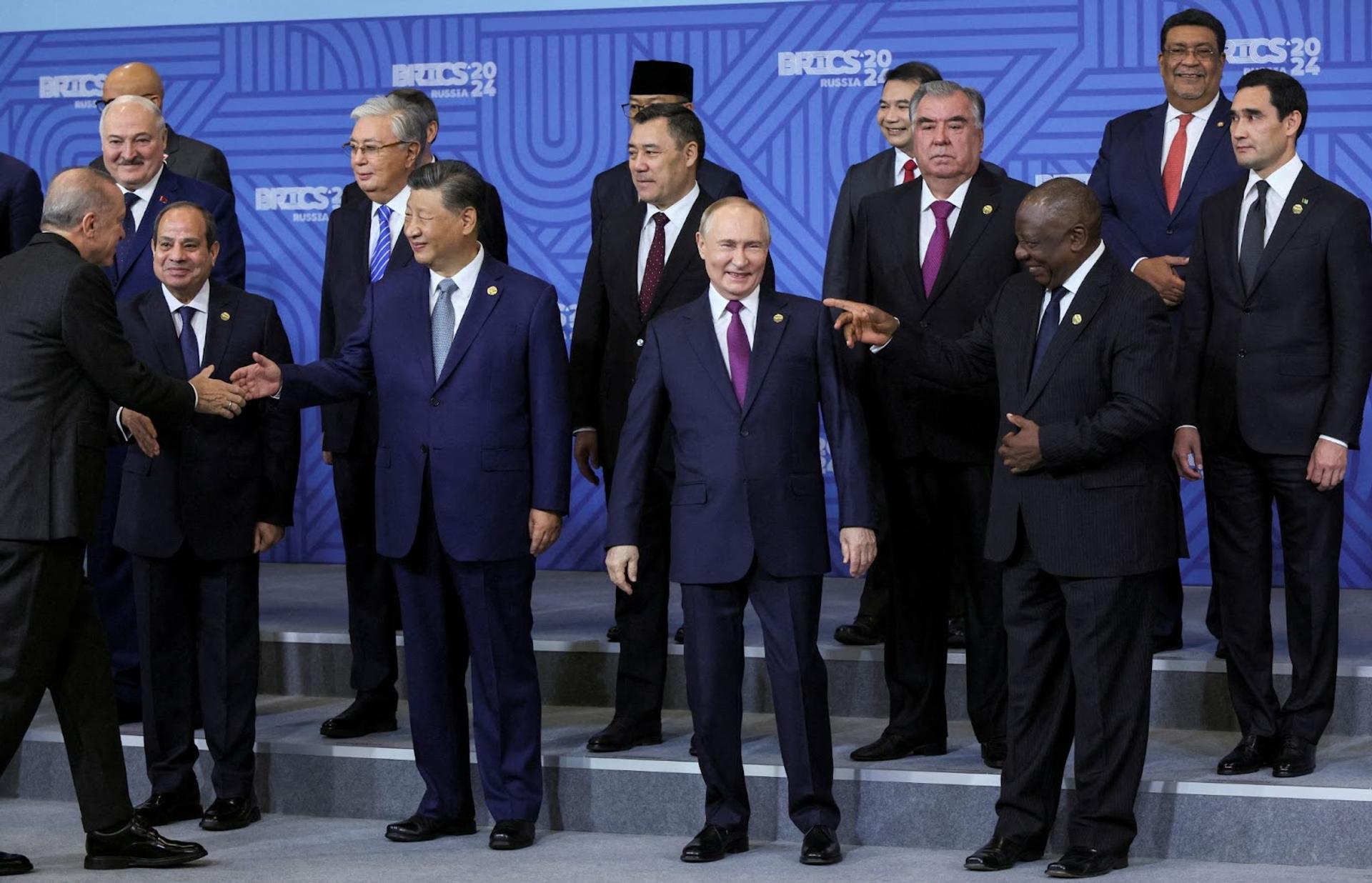 Vladimir Putin smiles as he poses for a family photo with other BRICS leaders including Xi Jinping in Kazan, Russia