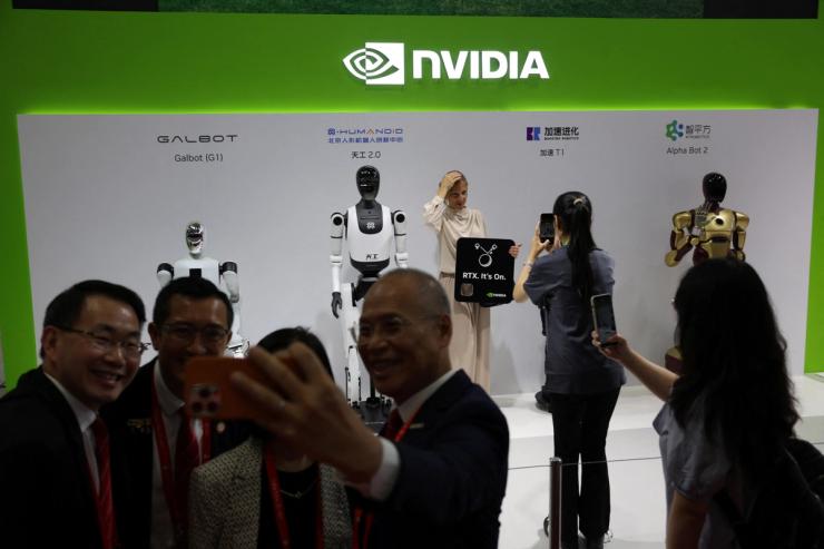 People take pictures with humanoid robots displayed at the Nvidia booth during the China International Supply Chain Expo in Beijing, China
