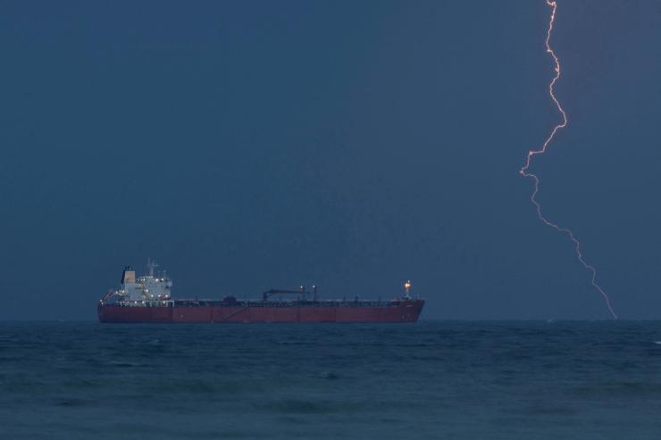 The tanker RARITY sits at anchor as lightning flashes in the distance.