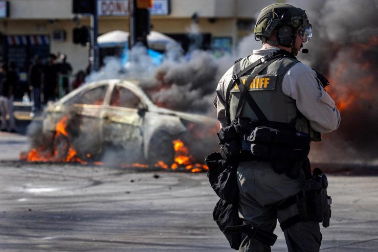 Smoke rises from a burning car on Atlantic Boulevard, during a standoff by protesters and law enforcement.