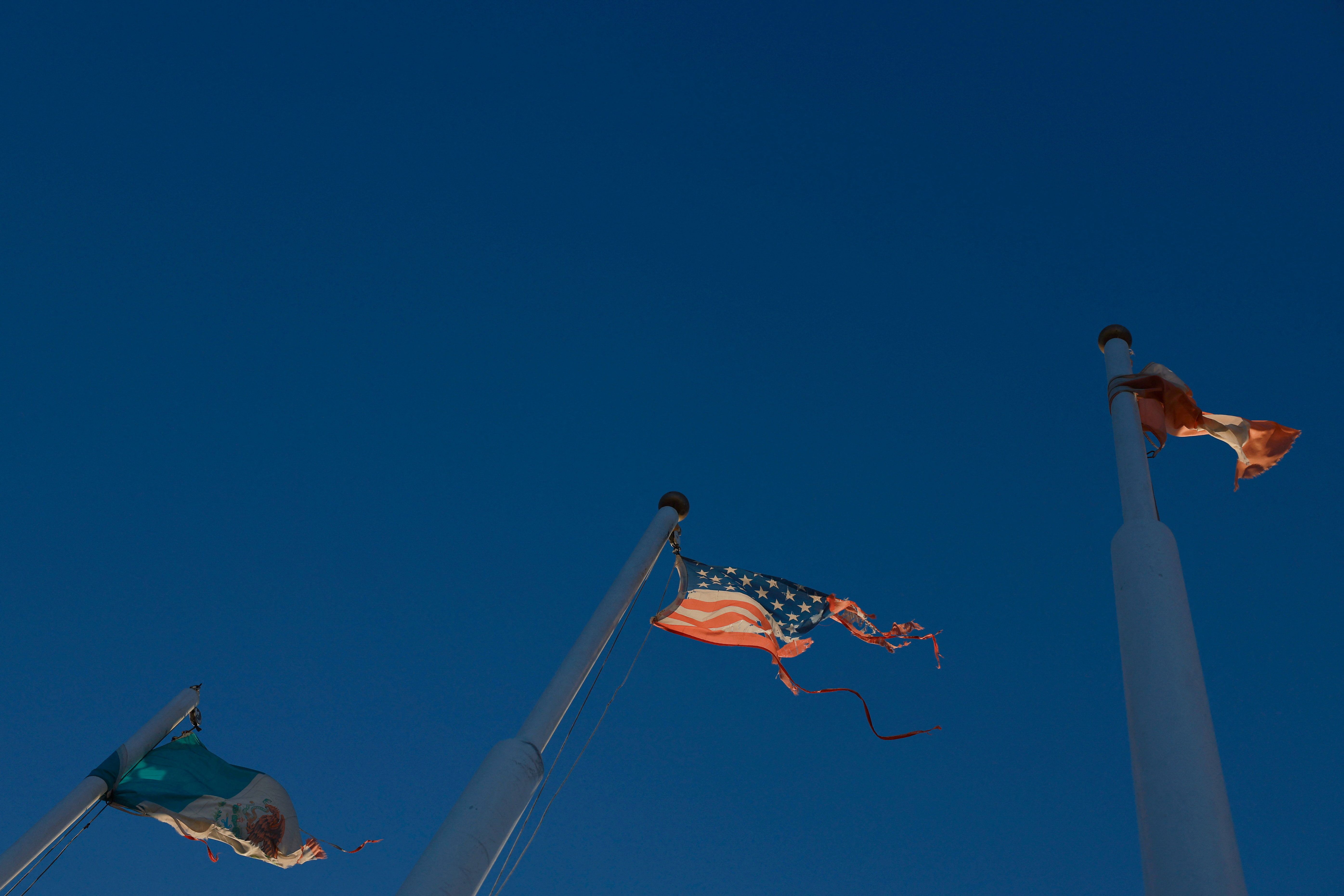 The flags of Mexico, the United States and Canada fly in a park.