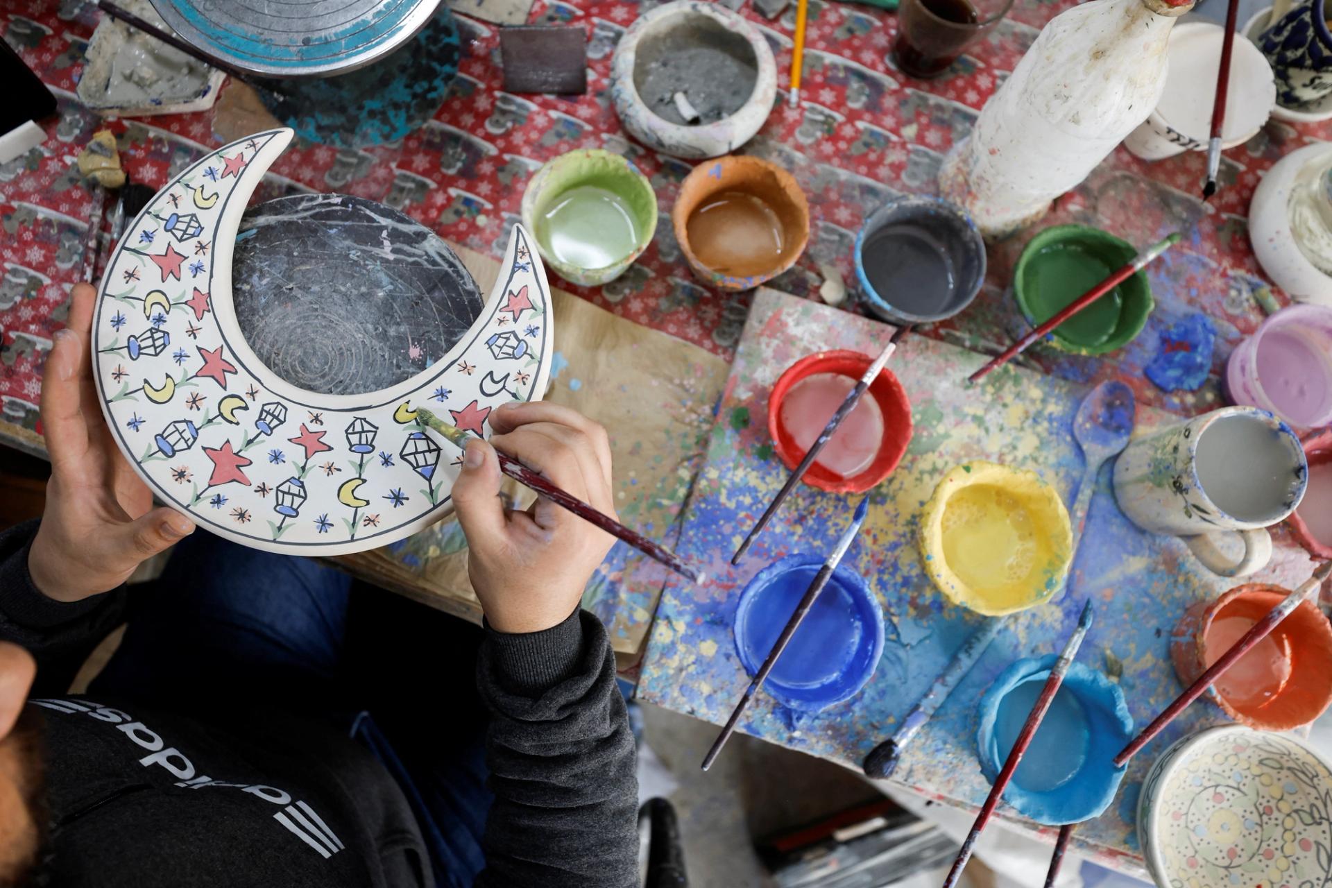 A Palestinian draws on ceramic utensils at a Palestinian shop ahead of Ramadan in Hebron in the Israeli-occupied West Bank March 15, 2023. REUTERS/Mussa Qawasma