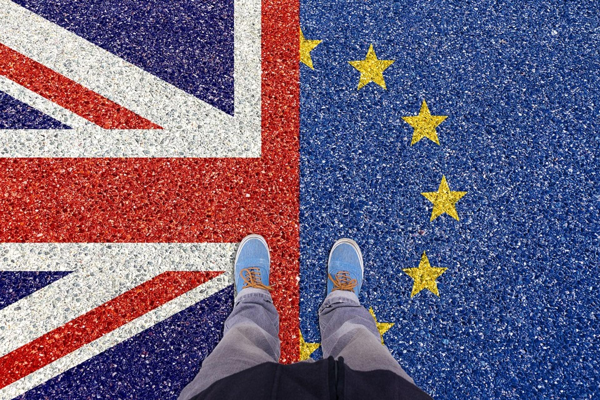 A person stands on a Union Jack and EU flag.